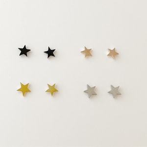 May include: Six pairs of star-shaped earrings in black, gold, and silver.