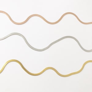 May include: Four herringbone chain necklaces in rose gold, silver, and gold tones, arranged in wavy lines against a white background. The chains have a flat, smooth appearance. The colours are evenly distributed.