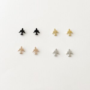 May include: Six pairs of airplane stud earrings in black, gold, rose gold, and silver.