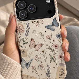 May include: A smartphone case with a cream-colored background featuring a botanical print of wildflowers, lavender sprigs, and butterflies in shades of blue and pink. The design includes vintage-style paper scraps with the text Carte Postale.