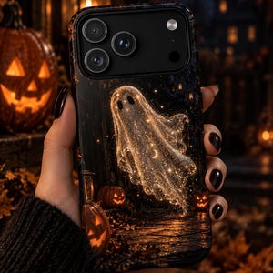 May include: A black smartphone case featuring a glowing, translucent ghost illustration filled with sparkling stars and a small crescent moon. The design depicts a dark, atmospheric Halloween scene with carved jack-o'-lanterns and autumn leaves.
