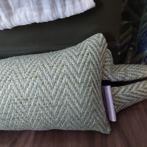 May include: A green and white patterned doorstop with a chevron design. The doorstop is made of fabric and has a white label attached to it.