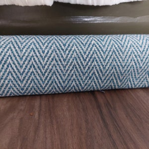 May include: A rolled up blue and white patterned rug with a herringbone design.