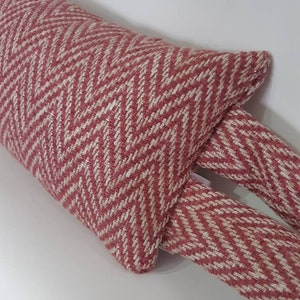 May include: A red and white chevron patterned doorstop with two long, thin tails.