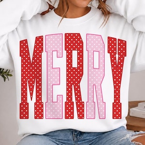 May include: A white long-sleeve crewneck sweatshirt featuring the word MERRY printed in large, block-style letters. The letters alternate between red and light pink, and each letter is decorated with a pattern of small white polka dots.