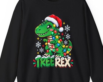 Op de afbeelding: Een zwart sweatshirt met lange mouwen en een afbeelding van een groene dinosaurus met een rood-witte kerstmuts, omwikkeld met kleurrijke kerstverlichting en omringd door witte sneeuwvlokken, met de tekst TREE REX eronder.