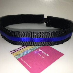 May include: Black headband with a single blue stripe. The headband is made of fabric and has a thin elastic band for a comfortable fit. The text "Hot Headz HEADBANDZ" is visible on a pink card.