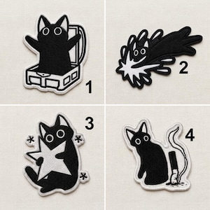 Puede incluir: Cuatro parches bordados en blanco y negro con un gato. El número 1 muestra un gato en una caja. El número 2 muestra un gato saltando con salpicaduras blancas. El número 3 muestra un gato sosteniendo una estrella. El número 4 muestra un gato con un cigarrillo.