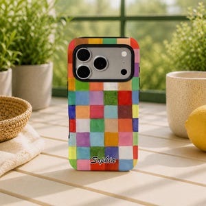 Puede incluir: Una funda rectangular para smartphone con un vibrante patrón de cuadrícula multicolor de cuadrados pintados a mano en tonos rojo, azul, verde, amarillo, naranja y morado. El nombre Sophia está impreso en letra cursiva negra cerca de la base.