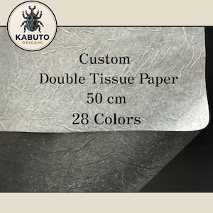 May include: A sheet of light gray, textured double tissue paper with a wrinkled surface. The text on the paper reads: Custom, Double Tissue Paper, 50 cm, 28 Colors. A circular logo in the top left corner features a beetle and the text KABUTO ORIGAMI.