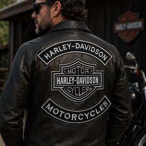 Pode incluir: Um casaco de couro preto com um grande emblema bordado da Harley-Davidson nas costas. O emblema inclui o texto Harley-Davidson, Motor Harley-Davidson Cycles e Motorcycles em bordado branco sobre um fundo preto.