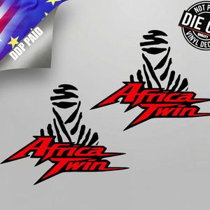 Può includere: Due adesivi in vinile fustellati con una grafica nera di una persona che indossa un copricapo sopra il testo rosso Africa Twin. Il design è nitido e angolare, con il testo posizionato orizzontalmente sotto l'icona nera del copricapo.