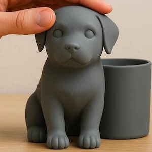 May include: A matte dark gray desk organizer featuring a sculpted puppy figure sitting upright next to a cylindrical container. The puppy has smooth, rounded features, floppy ears, and a neutral expression, integrated into a single solid piece.