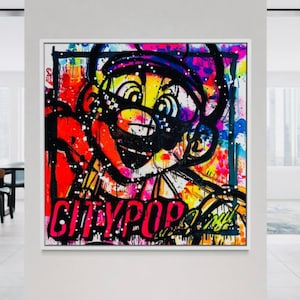 Op de afbeelding: Een vierkant canvas wandkunstwerk met een levendige graffiti-stijl illustratie van een stripfiguur met een snor. Het kunstwerk gebruikt gedurfde spatten rode, gele, blauwe en roze verf met de tekst CITYPOP in grote zwarte letters.
