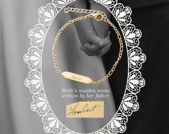 Op de afbeelding: Een goudkleurige kettingarmband met een centrale rechthoekige staaf gegraveerd met de cursieve naam Lambert. De armband is voorzien van een karabijnsluiting en een verstelbare verlengketting. De tekst Bride's maiden name written by her father is zichtbaar.