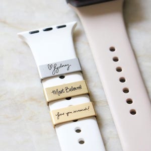 Może przedstawiać: Białe i blador&oacute;żowe paski do Apple Watch z grawerowanymi metalowymi akcentami. Akcenty zawierają frazy "Sydney", "Most Beloved" i "love you so much!".