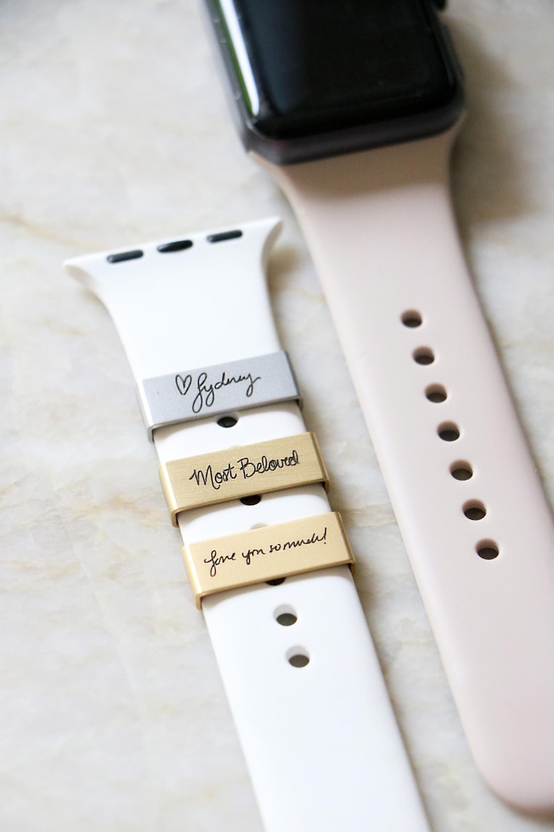 Może przedstawiać: Białe i blador&oacute;żowe paski do Apple Watch z grawerowanymi metalowymi akcentami. Akcenty zawierają frazy "Sydney", "Most Beloved" i "love you so much!".