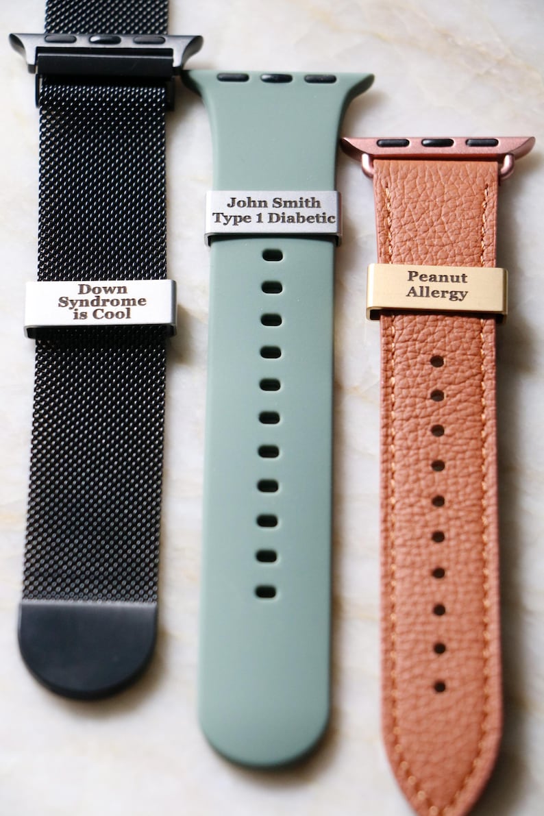 Może przedstawiać: Trzy paski do Apple Watch w układzie pionowym. Pierwszy to czarna siatka z napisem "Down Syndrome is Cool". Drugi to jasnozielony silikonowy pasek z napisem "John Smith Type 1 Diabetic". Trzeci to brązowy sk&oacute;rzany pasek z napisem "Peanut Allergy".
