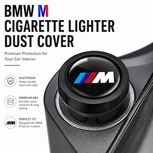 May include: A black BMW M cigarette lighter dust cover featuring the M logo in blue, red, and white. The circular cap has a glossy finish and is designed to fit into a car socket. Text on the image includes BMW M CIGARETTE LIGHTER DUST COVER.