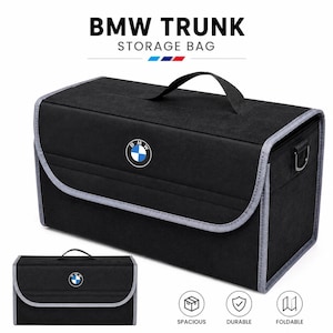 May include: A black BMW trunk storage bag with a top handle, grey trim, and the BMW logo on the front flap. The text BMW TRUNK STORAGE BAG appears at the top, with icons below labelled SPACIOUS, DURABLE, and FOLDABLE. A smaller view is shown below.