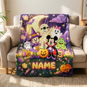 May include: A soft fleece blanket featuring a colorful Halloween scene with cartoon characters dressed in costumes, including a witch, a mummy, a vampire, and a ghost. The design includes pumpkins, candy, and the word NAME in large yellow letters.