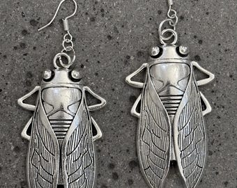 Orecchini pendenti a forma di cicala in argento della collezione “Keep it Wyrd”.