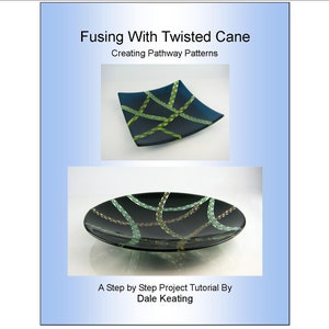 Puede incluir: Un tutorial de arte en vidrio titulado "Fusing With Twisted Cane: Creating Pathway Patterns" de Dale Keating. El tutorial presenta dos placas de vidrio con un fondo negro y diseños de caña retorcida verde y dorada.
