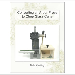 May include: A book cover with the title "Converting an Arbor Press to Chop Glass Cane" and the author's name, Dale Keating. The image shows an arbor press with a wooden box and glass pieces.