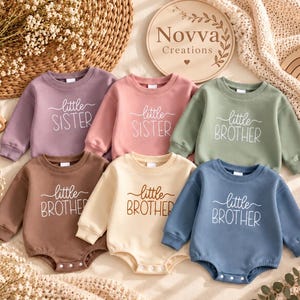 May include: A collection of six long-sleeved baby bodysuits and sweatshirts in various colors including purple, pink, sage green, brown, cream, and blue. Each garment features the white printed text little SISTER or little BROTHER.