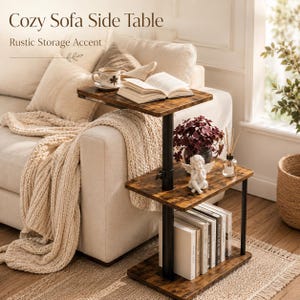 May include: A multi-level side table with a dark brown wood grain finish and black metal frame. The table features three rectangular shelves, with an open book on the top shelf, a small angel figurine on the middle shelf, and books on the bottom.