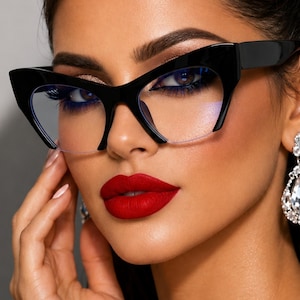 May include: Black cat-eye glasses featuring a thick, bold frame design with clear lenses. The glasses have an exaggerated upward-sweeping outer corner shape, providing a distinct silhouette that frames the eyes with a glossy, solid black finish.