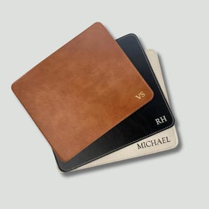May include: A stack of three square coasters in tan, black, and cream. The tan coaster features the gold embossed letters VS. The black coaster displays the white embossed letters RH. The cream coaster shows the black embossed name MICHAEL.