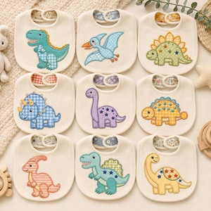 Può includere: Un set di nove bavaglini in tessuto color bianco sporco, ognuno caratterizzato da un unico disegno di dinosauro ricamato. I dinosauri sono decorati con vari motivi, tra cui quadretti vichy, righe e stelle in colori come verde, blu, viola, giallo e rosa.