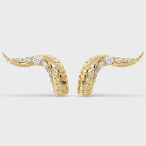 May include: A pair of curved gold earrings featuring a ribbed, horn-like texture along the outer edge. Each earring is accented with a row of small, round, clear white gemstones set along the inner curve, creating a bright, reflective finish.
