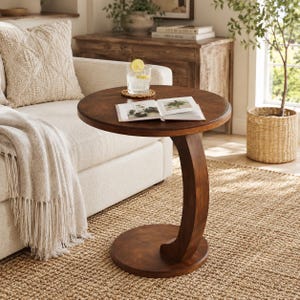 May include: A round, dark brown wooden side table with a C-shaped base. The table features a smooth, circular tabletop supported by a single curved pedestal that connects to a circular base, providing a stable structure for holding items.