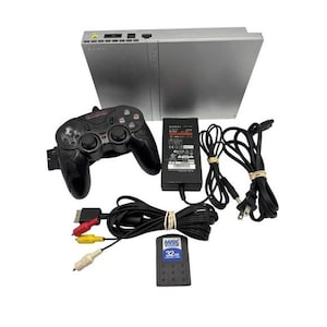 May include: A silver Sony PlayStation 2 console with a black third-party controller, a black power adapter, a black AV cable with red, yellow, and white connectors, and a black 32MB Max Memory card for data storage and gaming connectivity.