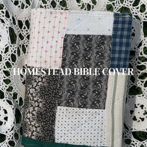 May include: A quilted fabric Bible cover featuring a patchwork design of various patterns including paisley, plaid, and small floral prints in shades of blue, white, and black, with a solid dark green border and the text HOMESTEAD BIBLE COVER.