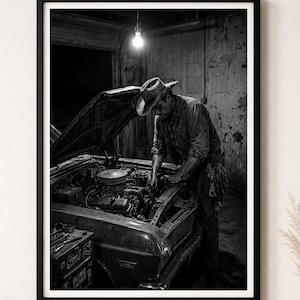 May include: A black and white framed wall art print depicting a mechanic wearing a cowboy hat while working on the engine of a vintage car inside a dimly lit garage, illuminated by a single hanging light bulb above the open vehicle hood.
