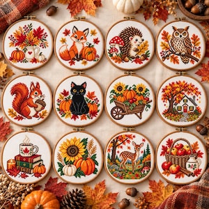 May include: Twelve circular wooden embroidery hoops containing cross-stitch designs featuring autumn themes, including a fox, hedgehog, owl, squirrel, black cat, deer, pumpkins, sunflowers, a house, a basket of apples, and stacks of books.