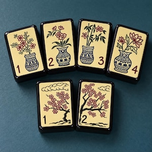 May include: Six rectangular mahjong tiles with a cream-colored face and dark brown back. The top row features four tiles numbered 1 through 4, each displaying a floral arrangement in a blue and white vase. The bottom row shows two tiles numbered 1 and 2.