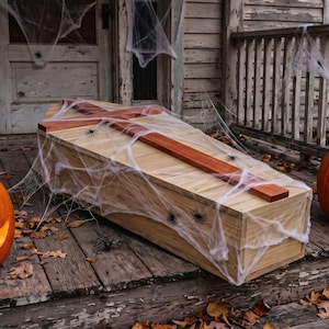 May include: A wooden coffin with a cross on the lid, draped in artificial spider webs with small plastic spiders. Two carved orange jack-o'-lanterns with glowing faces sit on either side. Text reads: Buy one get one free, Etsy exclusive, digital file product.