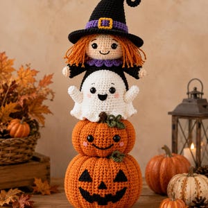 May include: A vertical stack of four crocheted figures: a witch with orange hair and a black hat, a white ghost, a small orange pumpkin with a smiling face, and a large orange jack-o'-lantern with a carved black face, all made of yarn.