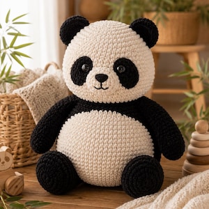Puede incluir: Un peluche de panda elaborado con hilo color crema y negro mediante una técnica de ganchillo. El panda presenta una cabeza redonda con manchas negras alrededor de los ojos, orejas pequeñas negras, nariz negra y boca bordada, con una barriga crema.