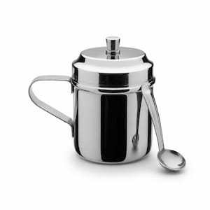 May include: A polished stainless steel canister with a cylindrical body, a flat handle on the side, and a removable lid featuring a small central knob. A matching stainless steel spoon is hooked onto the side of the canister, resting against it.