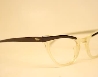 May include: A pair of vintage cat-eye spectacles. The frames are a translucent cream colour with dark brown accents on the top and arms. The spectacles have a classic, retro design.