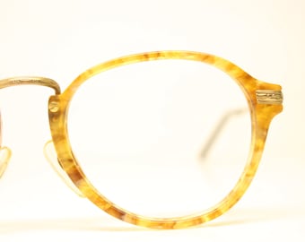 Puede incluir: Un par de gafas redondas de carey con detalles dorados.