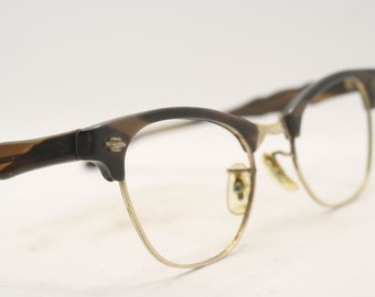 May include: A pair of vintage brown and gold eyeglasses with a cat-eye frame.
