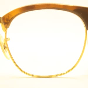 May include: A pair of gold-rimmed glasses with brown tortoise shell frames.