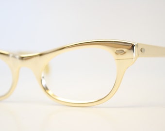 May include: Gold-tone cat-eye glasses with a thin metal frame.