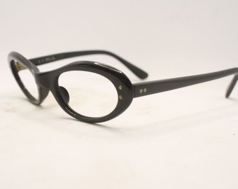 May include: Black oval-shaped eyeglasses with gold accents on the temples.